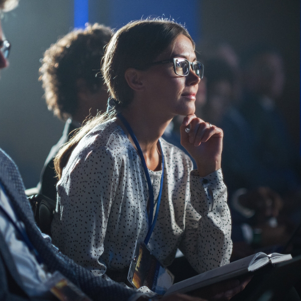 A young woman listens intently to an event speaker.